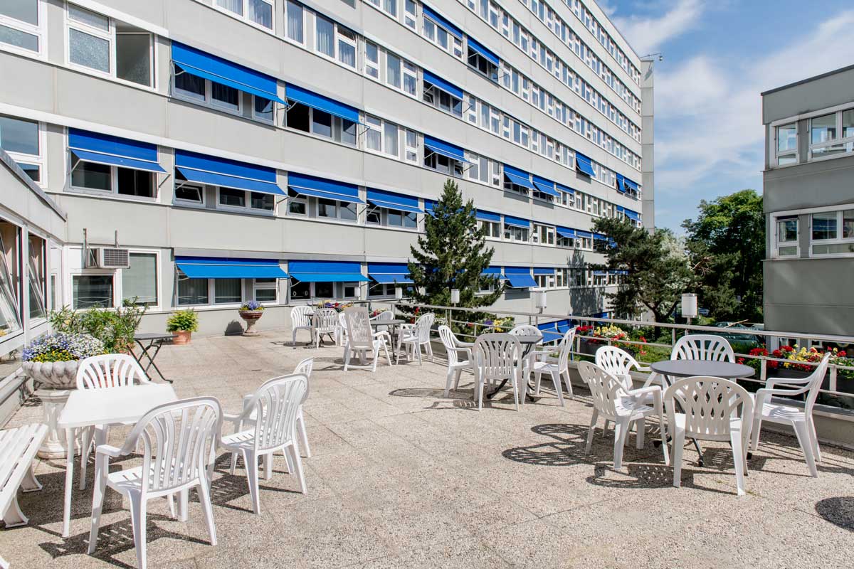 Teaserbild des Berufliche Rehabilitation Standort Charlottenburg mit Terasse auf dem Tisch und Stühle stehen